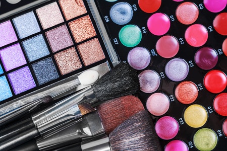Pallet of eye shadows in bright colors with some make up brushes at the bottom of the image.