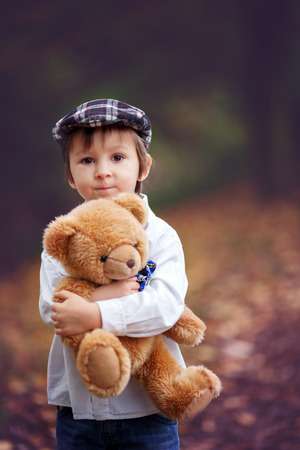 Little boy with suitcase and teddy bear in park