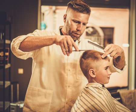  menino que visita o hairstylist na barbearia