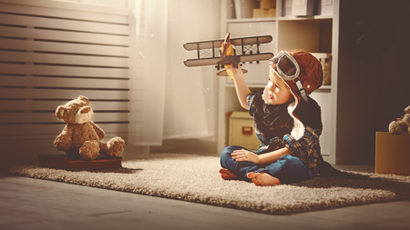 aviador criança com um avião de brinquedo joga em casa em seu quarto