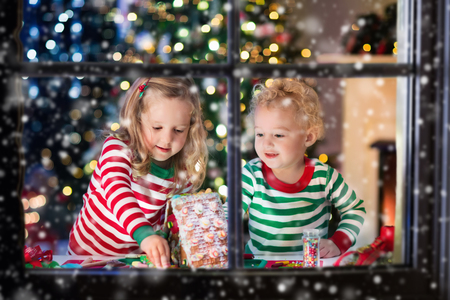  Bambini che giocano con il pane allo zenzero sotto l'albero di Natale.