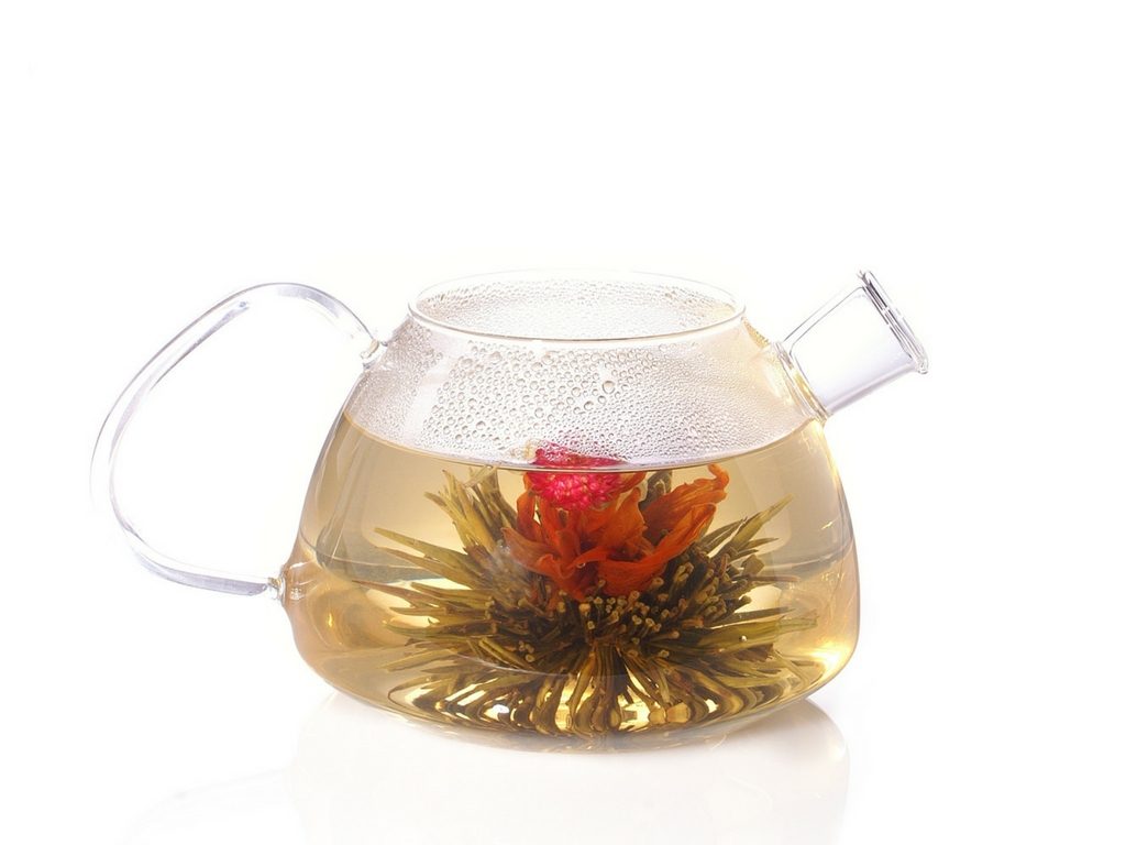 Flowering tea in a clear teapot with a thin handle.