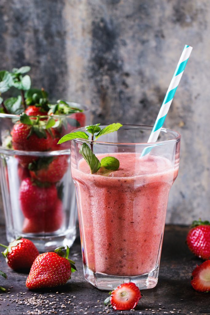 Strawberry Chia Smoothie in a clear cup with a blue and white paper straw.