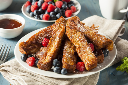 Plate of french toast sticks surrounded by blueberries and raspberries.