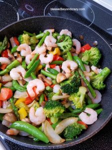 Deep pan filled with assorted vegetables and some shrimp.