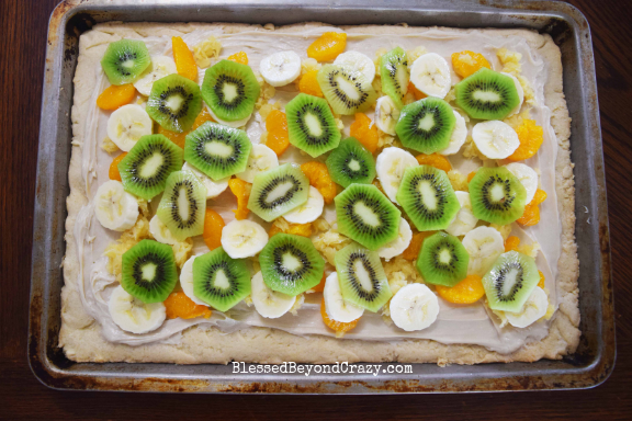 Layering Mandarin oranges, banana, and kiwi on The Ultimate Loaded Fruit Pizza