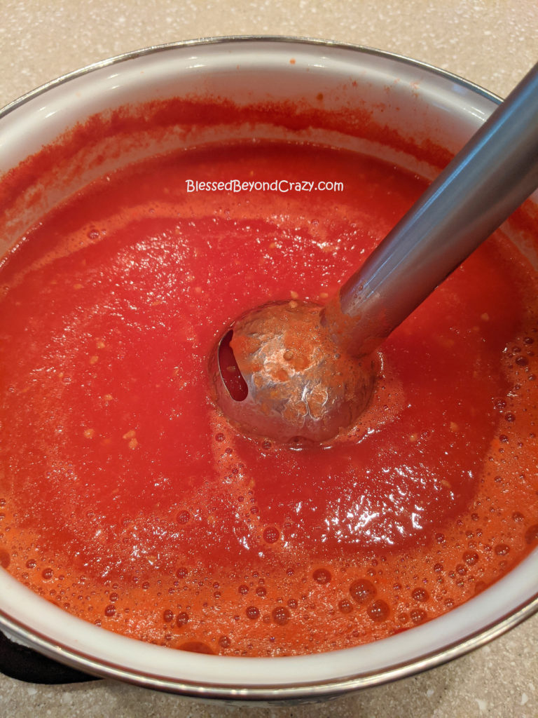 Using an immersion blender to puree tomatoes for Homemade Sausage Tomato Soup (Gluten-Free Option)