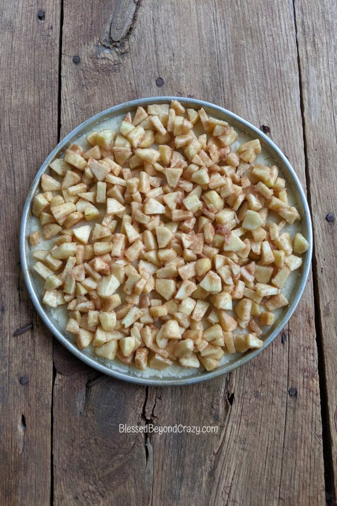 Chopped apples on top of pie crust for apple dessert pizza