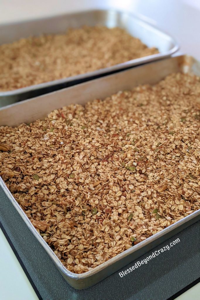 Two large baking pans filled with granola ready to bake.