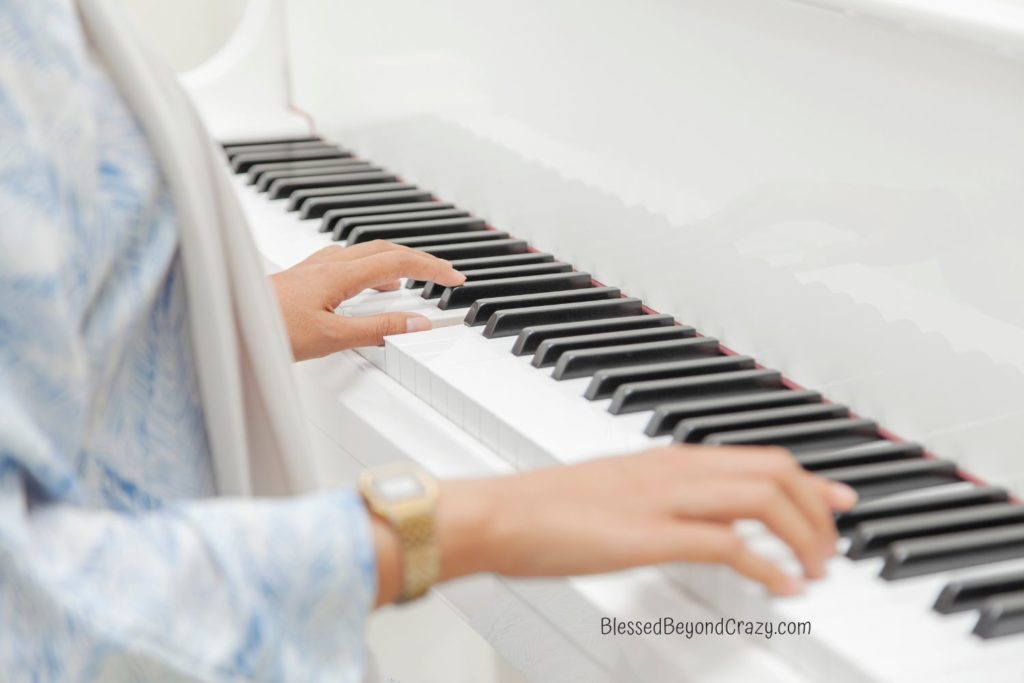 Woman's hands playing a white piano