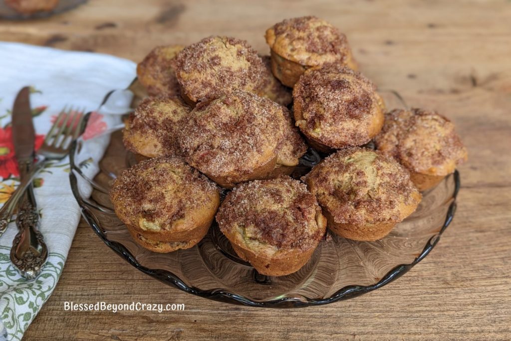 Fresh rhubarb muffins stacked on a pretty glass serving tray.