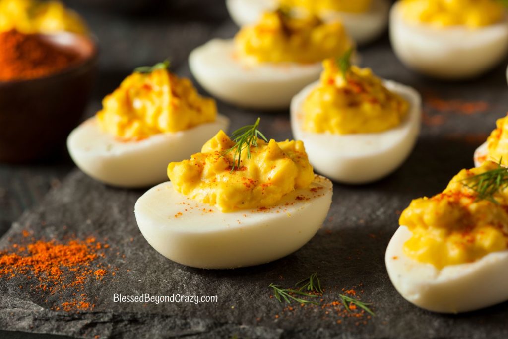 Side view of deviled eggs resting on a slate platter.