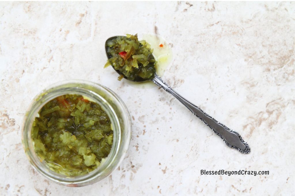 Overhead view of jar of homemade sweet pickle relish and a spoonful on the side.