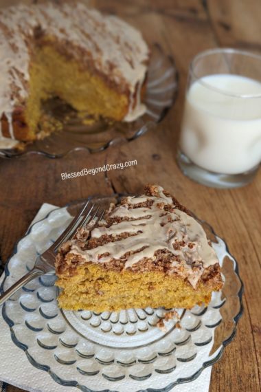 Delicious slice of cake ready to eat with entire cake in background.