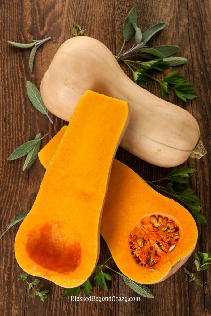 A fresh butternut squash cut in half to expose yellow flesh and seeds.