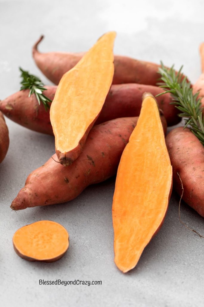 Sweet Potatoes in a pile with one cut in half.