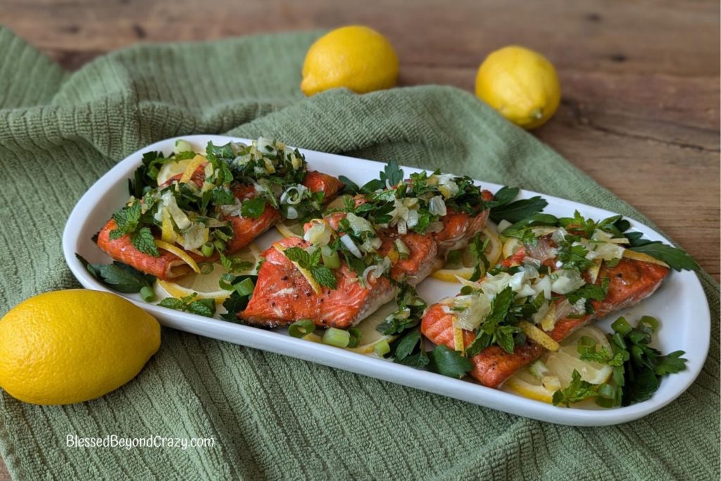 Horizontal view of platter with salmon steaks, lemon salsa, and fresh lemons.