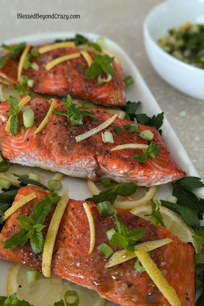 Close up photo of three Sockeye salmon steaks with herbs and slivers of lemon rind.