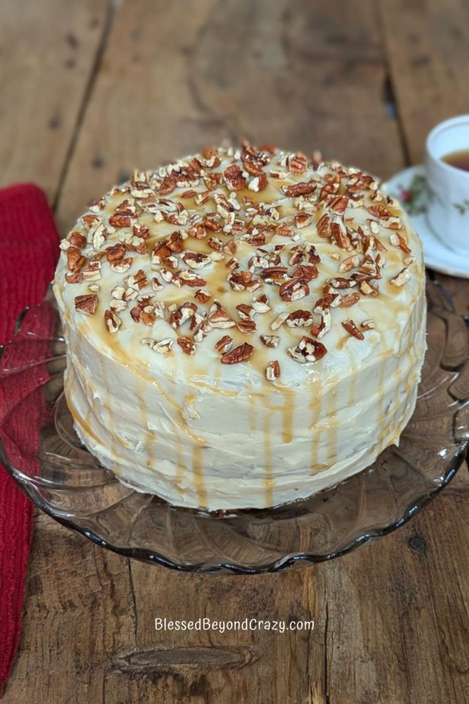 Photo of entire precut cranberry pineapple pecan carrot cake on a pretty glass serving platter.