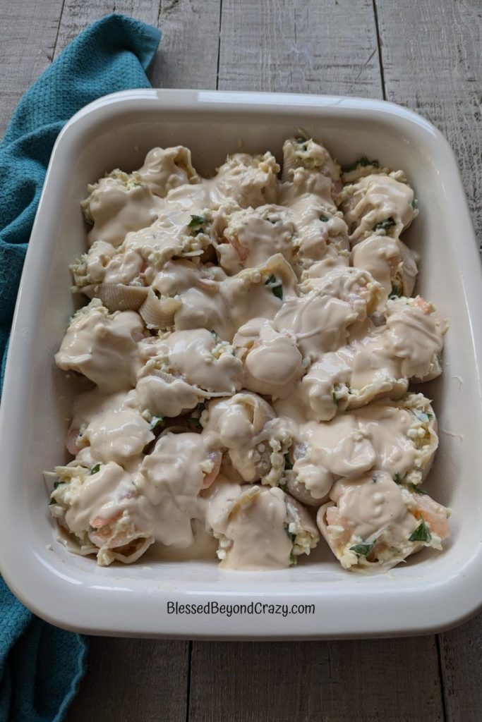 Overhead view of casserole dish filled with stuffed pasta with shrimp, crab, and herbs.