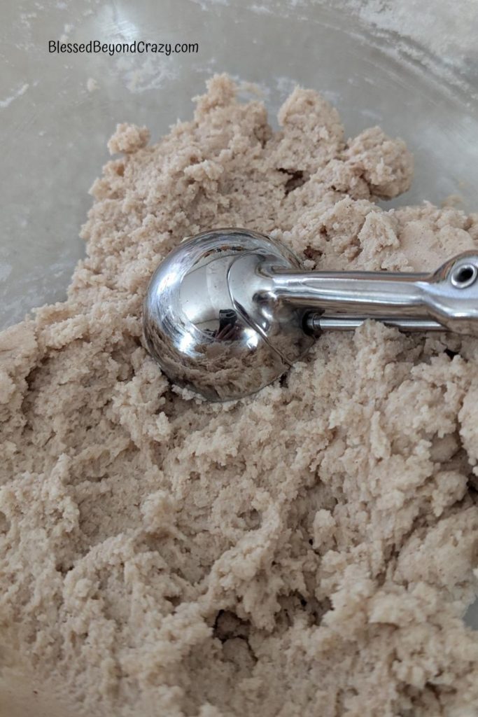 Cookie Scoop in a glass bowl with batter for potato drop doughnuts.