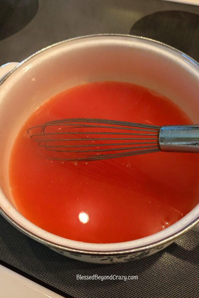 Saucepan with hot mixture of orange gelatin, vanilla pudding, and water.