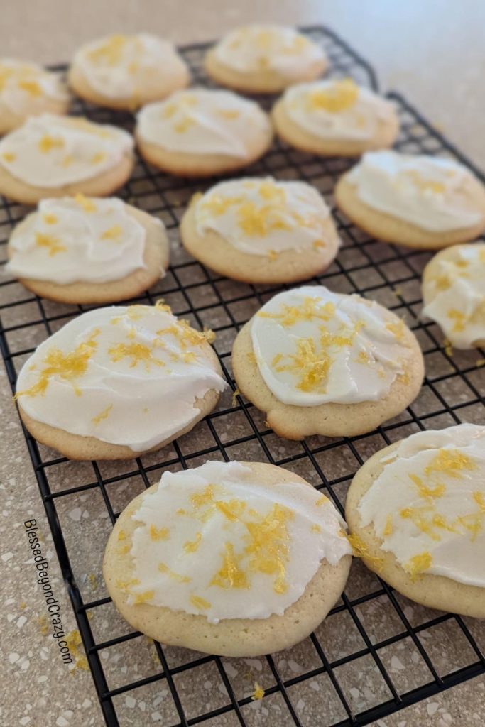 Lemon cookies with icing cooling on wire rack.