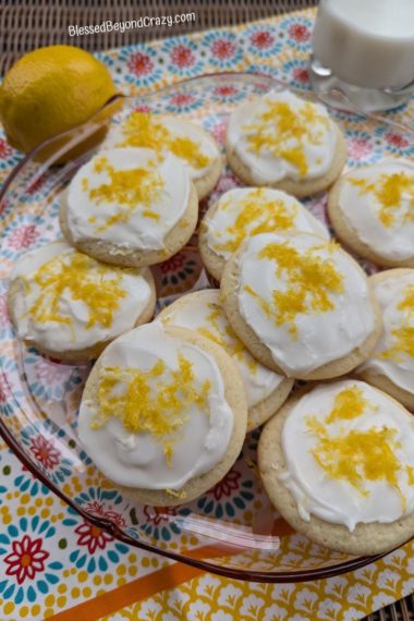 Serving platter with cookies, fresh whole lemon, and glass of milk.