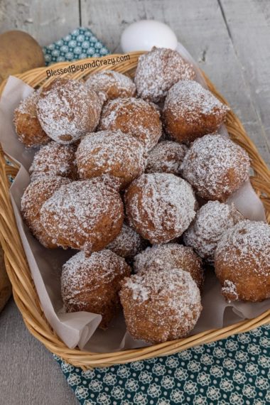 Basket full of sugared potato doughnuts with pretty dish towel underneath.