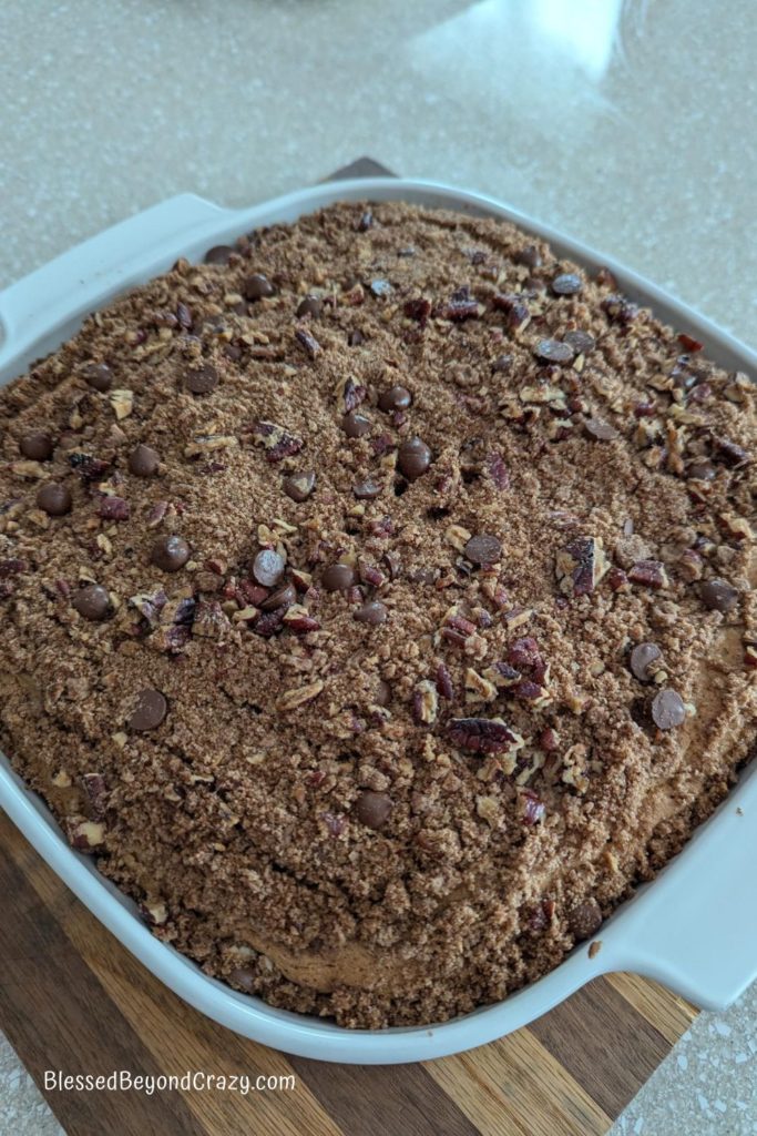 Freshly baked chocolate chip coffee cake cooling on wooden cutting board.