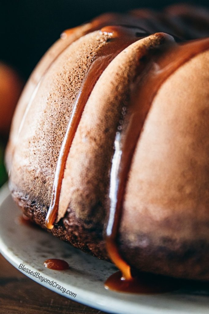 Close up photo of homemade caramel sauce running down the sides of an apple cider spice cake.