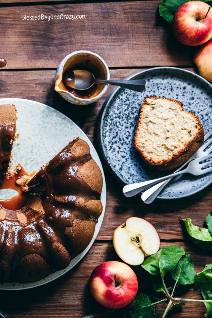 Overhead photo of half of an apple cider spice cake with a single serving of cake on a small plate.