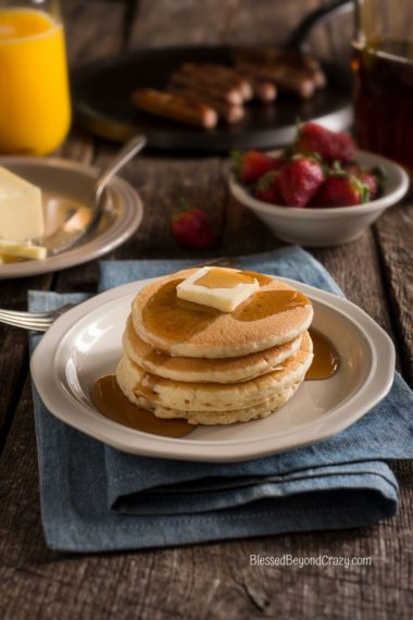 Vertical photo of four buttermilk pancakes ready to eat.