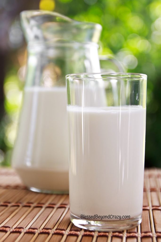 Photo of a glass pitcher of milk in the background and a glass of milk in the foreground.