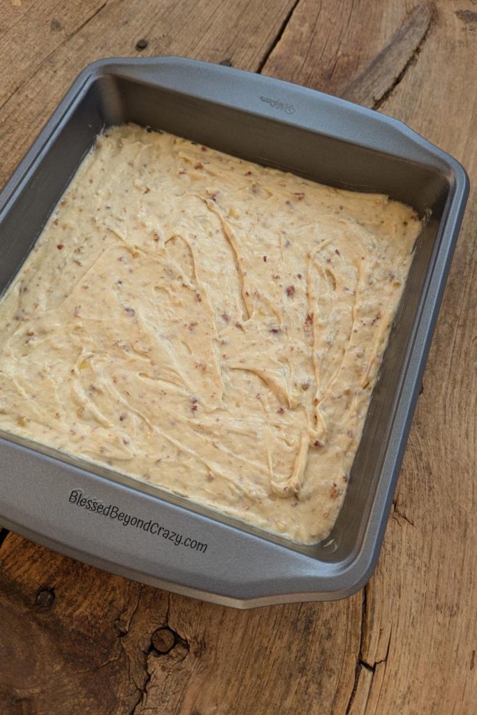 Overhead view of banana pecan cake batter in a square baking pan ready to place in the oven.