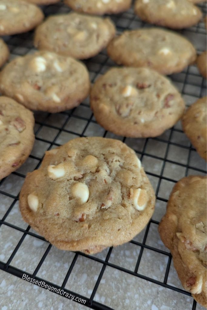 Close up view of white chocolate pecan cookies cooling on a wire rack.