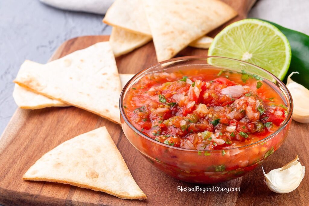 Horizontal photo of chips, bowl of salsa, fresh lime and jalapeno